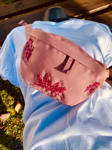 Sac banane rose brodé de motifs fleuris en fuchsia.