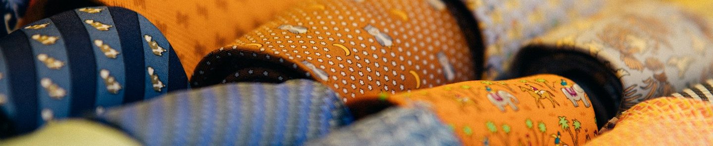 Cravates colorées disposées en rangées, présentant divers motifs et textures. Cravates colorées disposées en rangées, présentant divers motifs et textures.